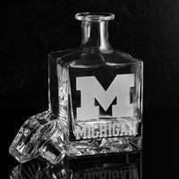 A clear crystal glass decanter with University of Michigan logo etched into the glass