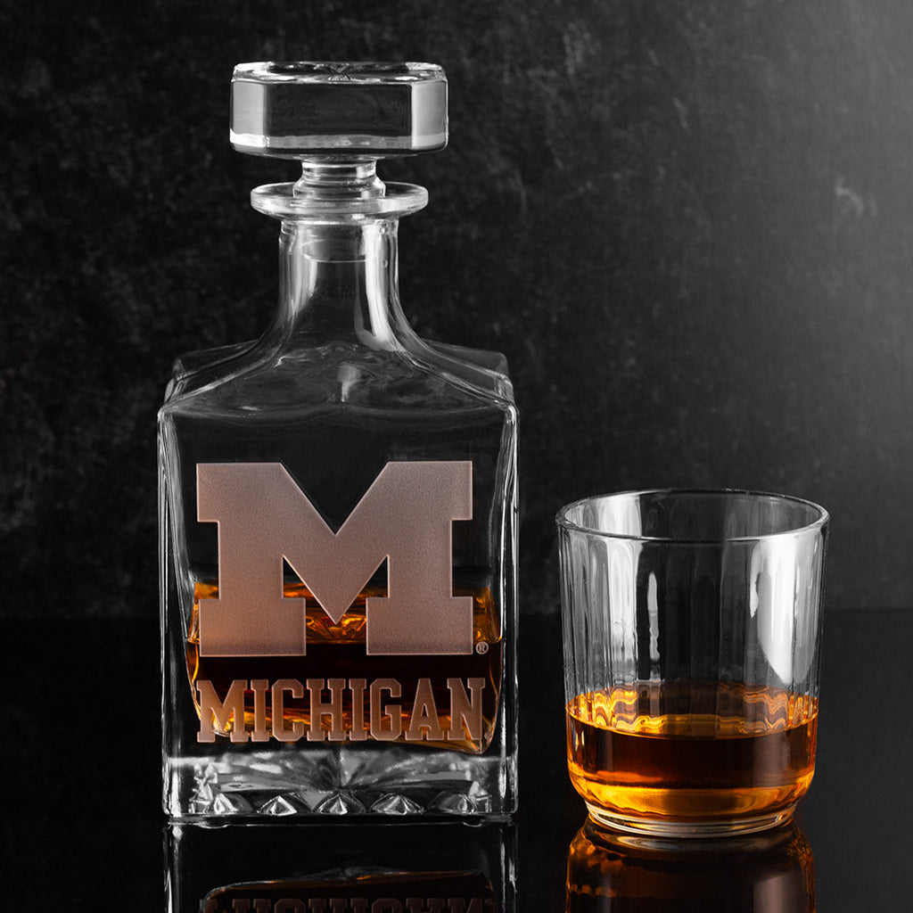Glass decanter with University of Michigan logo etched into the glass filled with bourbon whiskey