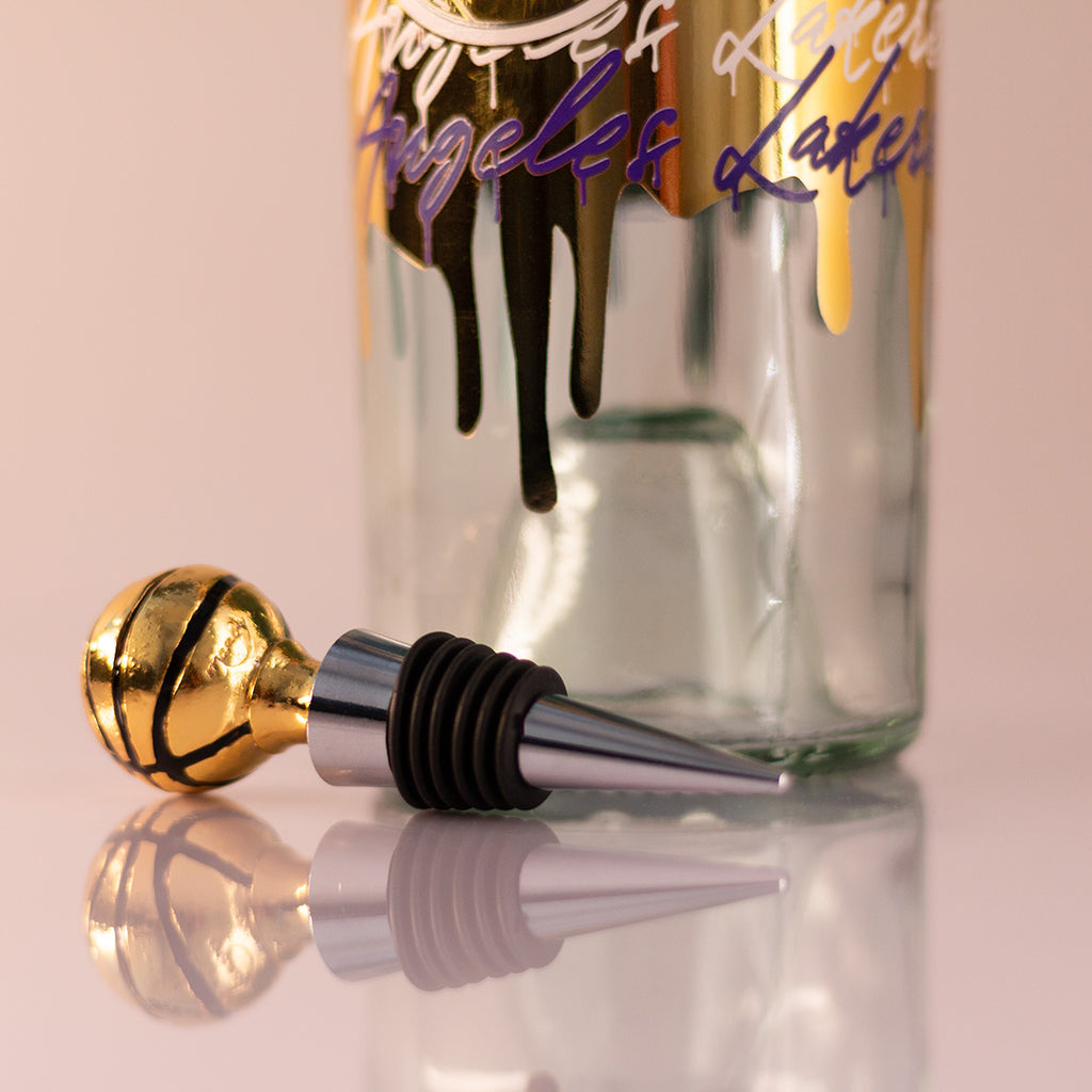 Gold basketball wine topper next to Los Angeles Lakers gold drip display wine bottle