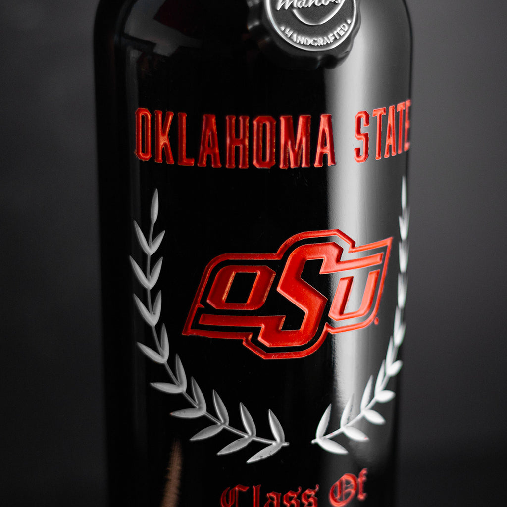 Close up view of red wine bottle etched with Oklahoma State, orange OSU logo, graduating class and custom name