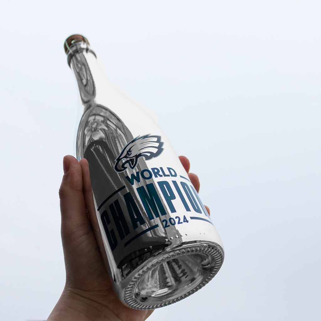 Person holding up a Philadelphia Eagles 2024 World Champions metallic silver bubbly wine bottle