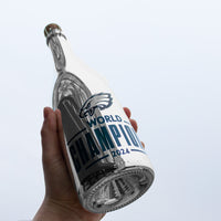Person holding up a Philadelphia Eagles 2024 World Champions metallic silver bubbly wine bottle