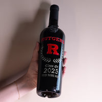 Hand holding up a Rutgers University bottle of red wine etched with class of 2025 and custom name