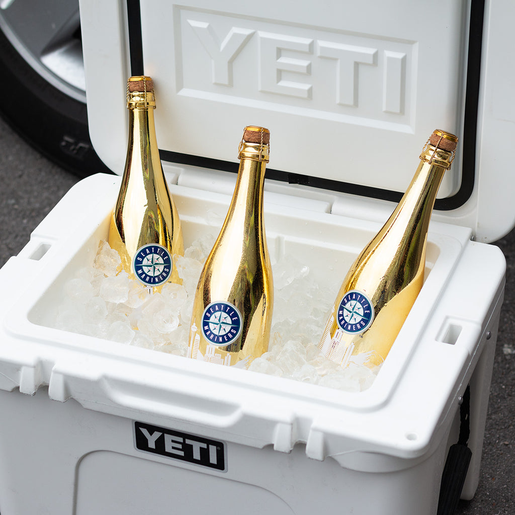 Three metallic silver Mano's Wine bottles of Seattle Mariners bubbly wines in a YETI cooler