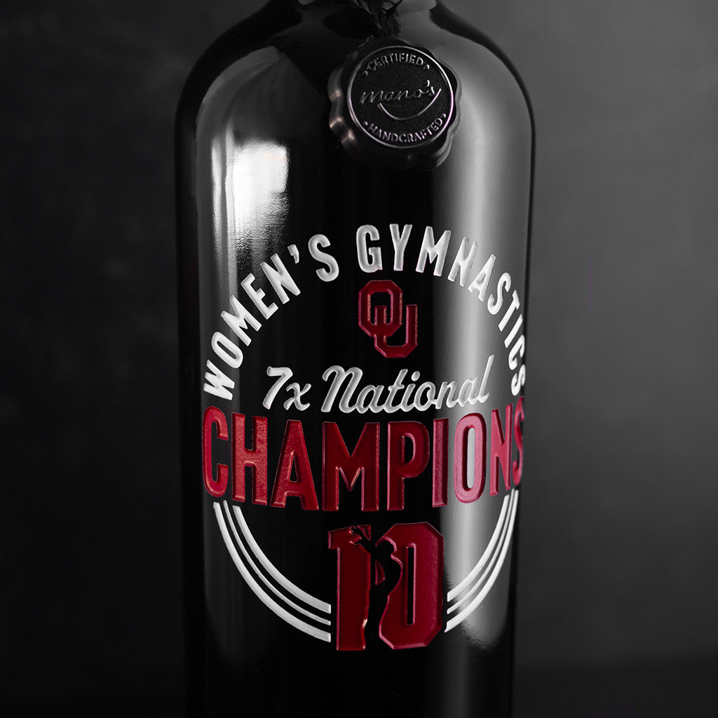 University of Oklahoma Women's Gymnastics 7x National Champions with cheerleader on the wine bottle