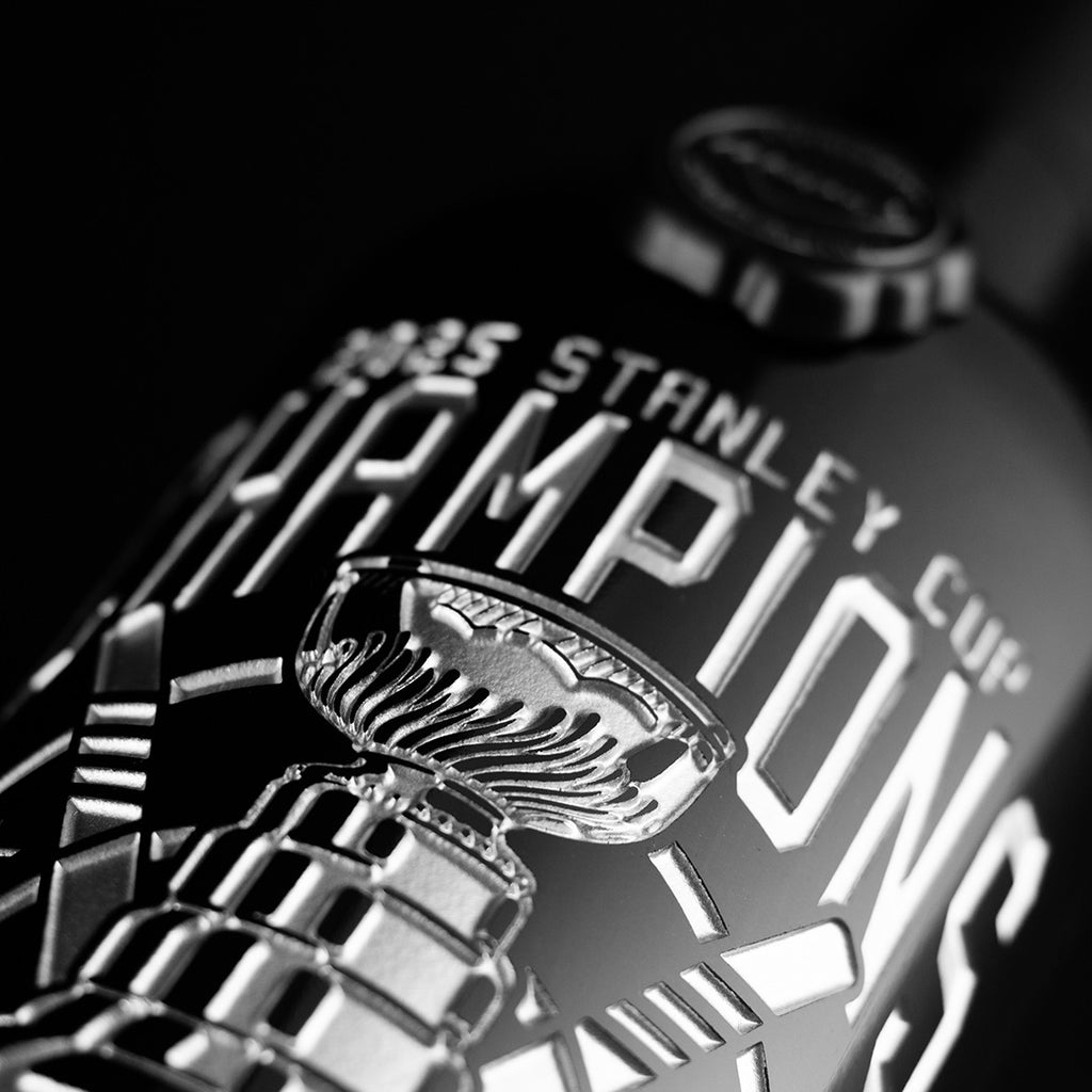 Silver text of 2025 Stanley Cup Champions and trophy etched on Mano's Wine cabernet sauvignon wine bottle