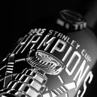 Silver text of 2025 Stanley Cup Champions and trophy etched on Mano's Wine cabernet sauvignon wine bottle