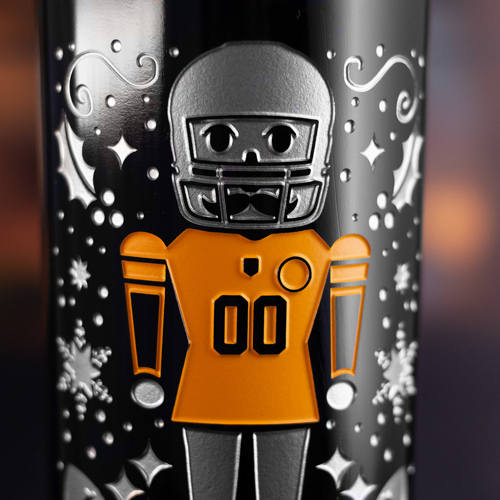 Steelers nutcracker wearing a football helmet and gold jersey and festive holiday deep etched designs on a wine bottle