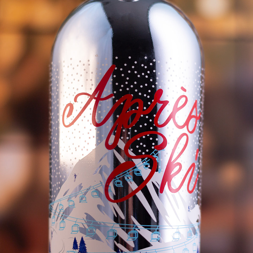 Metallic bottle with 'Apres Ski' text and ski slope design