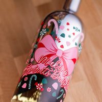 Close up of festive holiday bottle with pink bow, gum drops, candy canes and "Making Spirits Bright" text