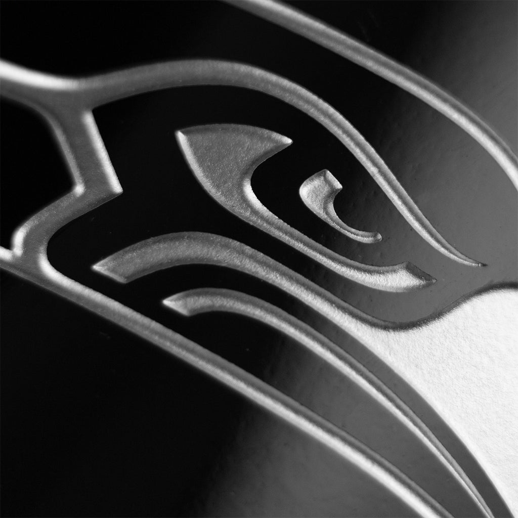 Close up of Seattle Seahawks team logo etched in silver on a Mano's Wine bottle