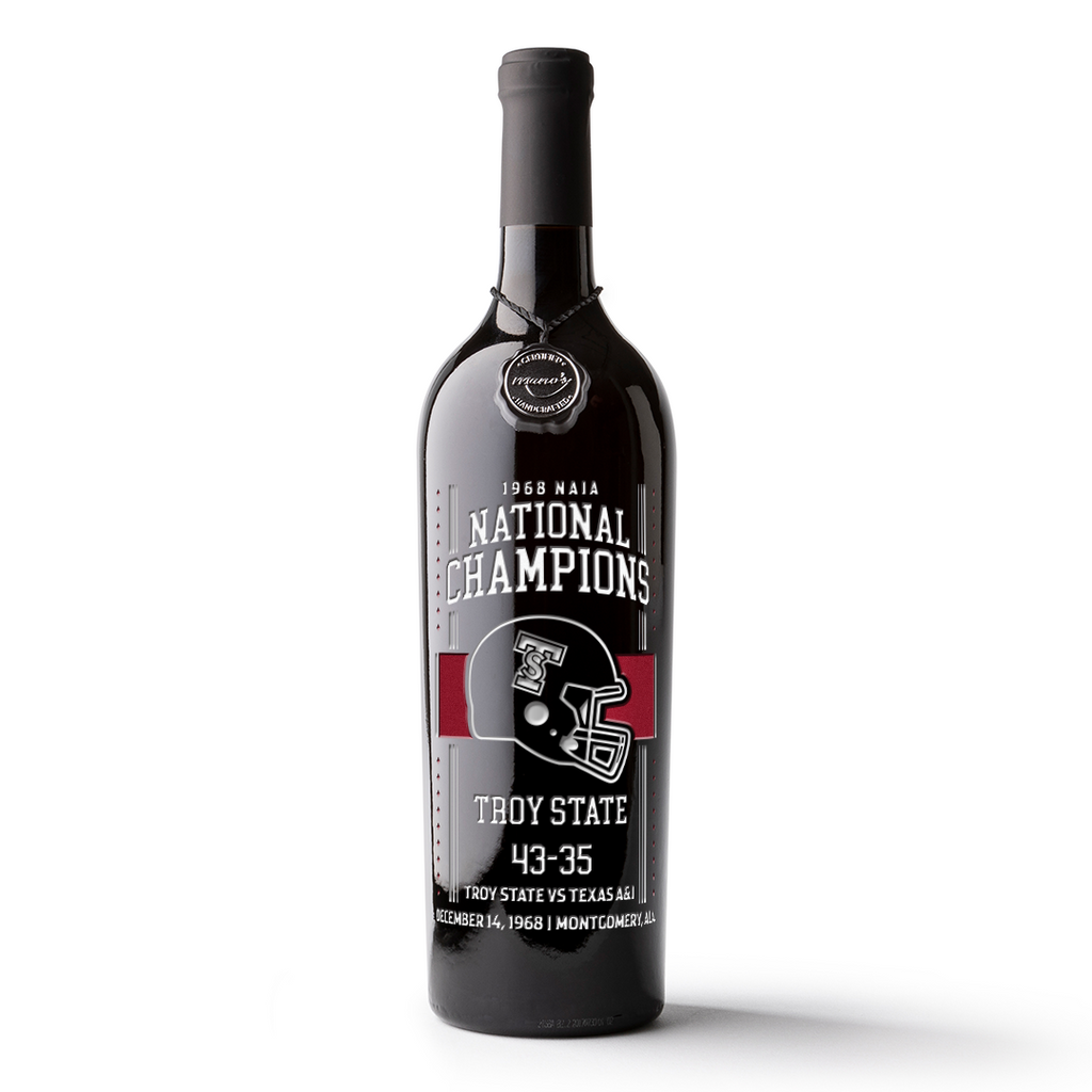 An etched wine bottle with Troy University 1968 Football Champions branding with a black, red and white text and helmet.